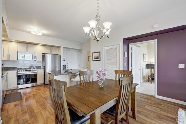 54 Rainey St Unit 814, Austin, TX 78701 - dining area featuring light wood-type flooring, a chandelier, and baseboards