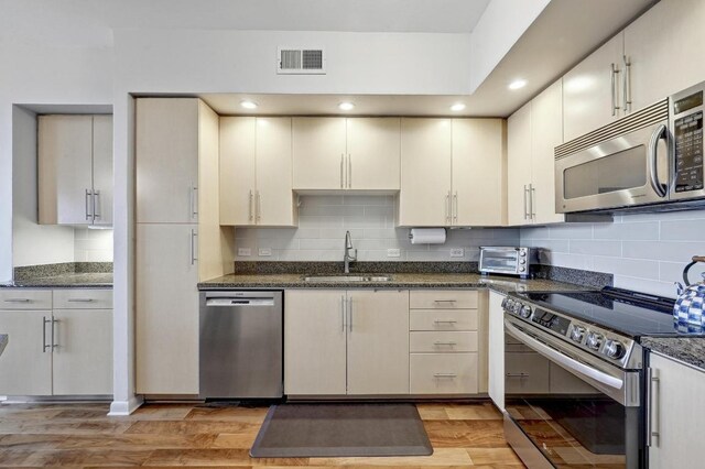 54 Rainey St Unit 814, Austin, TX 78701 - kitchen featuring a sink, appliances with stainless steel finishes, light wood-style flooring, decorative backsplash, and recessed lighting