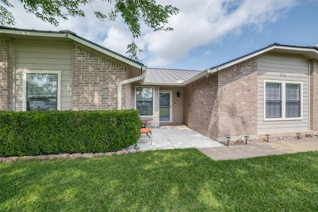 211 Spring Garden Dr, Hutto, TX 78634 - view of exterior entry with a yard, a patio area, and brick siding