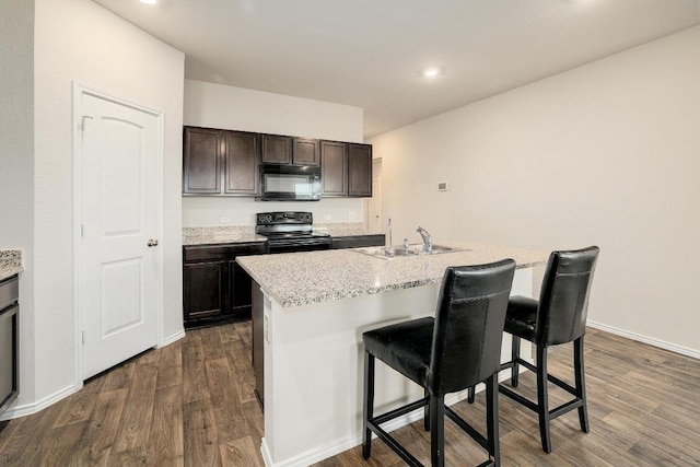 15000 Upland Willow Rd, Austin, TX 78724 - kitchen featuring black appliances, a sink, dark wood-type flooring, a kitchen breakfast bar, and a center island with sink