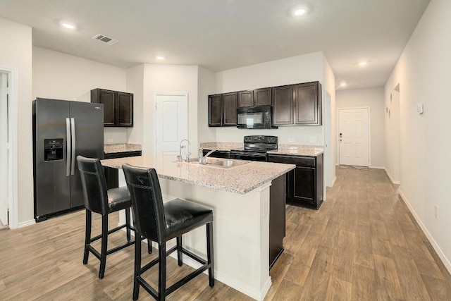15000 Upland Willow Rd, Austin, TX 78724 - kitchen featuring black appliances, light wood-type flooring, a breakfast bar, and recessed lighting