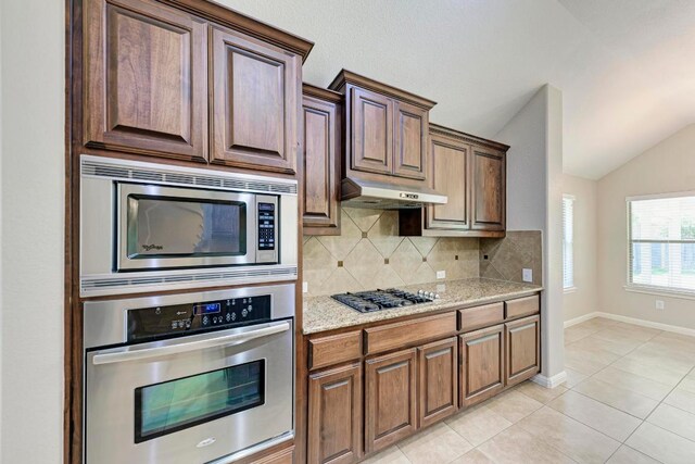 1803 Valle Verde Dr, Cedar Park, TX 78641 - kitchen with appliances with stainless steel finishes, lofted ceiling, backsplash, under cabinet range hood, and light tile patterned floors