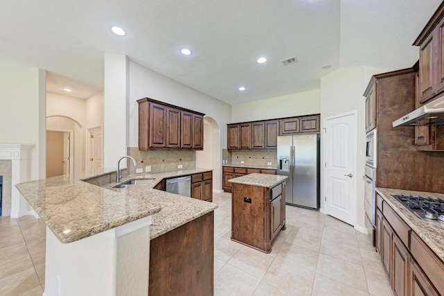 1803 Valle Verde Dr, Cedar Park, TX 78641 - kitchen featuring appliances with stainless steel finishes, arched walkways, a sink, tasteful backsplash, and a kitchen island