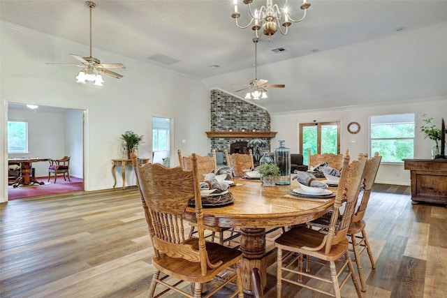 900 Cedar Park Dr, Cedar Park, TX 78613 - dining room featuring vaulted ceiling, a ceiling fan, light wood-style floors, a large fireplace, and a chandelier