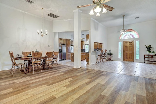 900 Cedar Park Dr, Cedar Park, TX 78613 - dining room featuring a towering ceiling, a ceiling fan, light wood finished floors, crown molding, and a chandelier