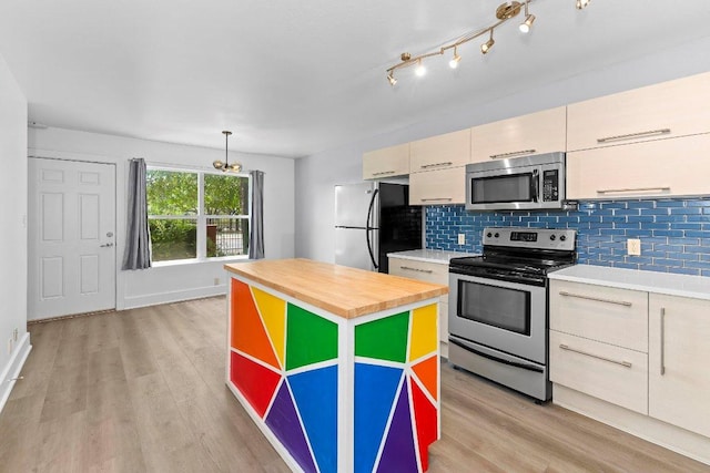 1101 Grove Blvd Unit 803, Austin, TX 78741 - kitchen with appliances with stainless steel finishes, decorative backsplash, light wood-style floors, wooden counters, and a center island