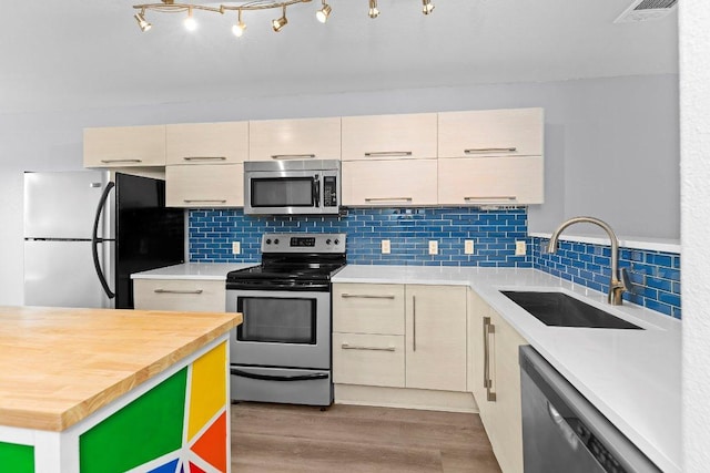 1101 Grove Blvd Unit 803, Austin, TX 78741 - kitchen with appliances with stainless steel finishes, a sink, wood finished floors, butcher block countertops, and tasteful backsplash
