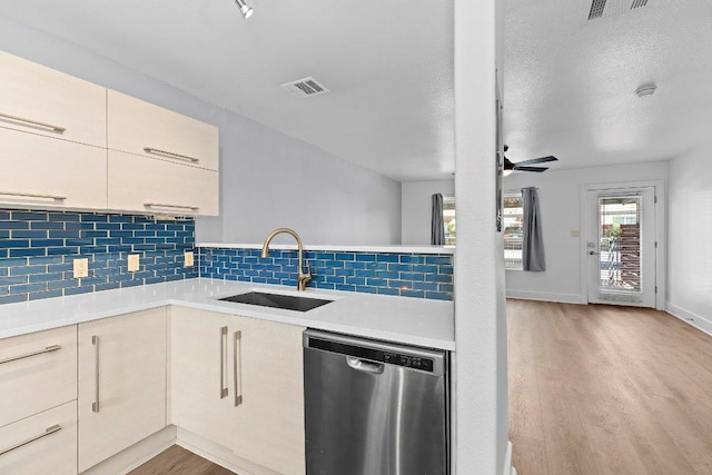 1101 Grove Blvd Unit 803, Austin, TX 78741 - kitchen with stainless steel dishwasher, a sink, light wood-type flooring, light countertops, and decorative backsplash