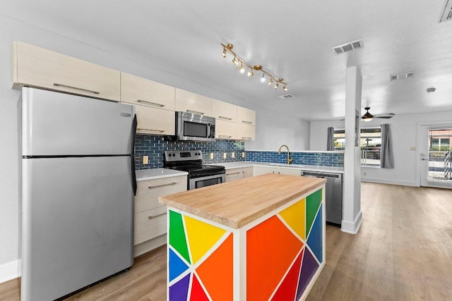 1101 Grove Blvd Unit 803, Austin, TX 78741 - kitchen with stainless steel appliances, decorative backsplash, light wood-type flooring, a ceiling fan, and a kitchen island