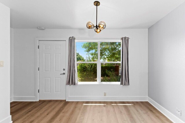 1101 Grove Blvd Unit 803, Austin, TX 78741 - unfurnished dining area featuring light wood-type flooring, a chandelier, and baseboards