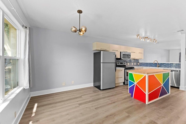 1101 Grove Blvd Unit 803, Austin, TX 78741 - kitchen featuring stainless steel appliances, decorative backsplash, a sink, light wood finished floors, and a chandelier