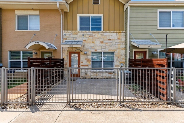 1101 Grove Blvd Unit 803, Austin, TX 78741 - view of property featuring stone siding, board and batten siding, a gate, and a fenced front yard