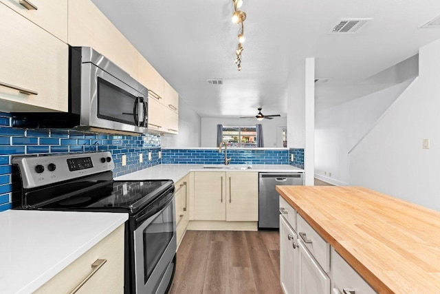 1101 Grove Blvd Unit 803, Austin, TX 78741 - kitchen with stainless steel appliances, wood counters, dark wood finished floors, a sink, and backsplash