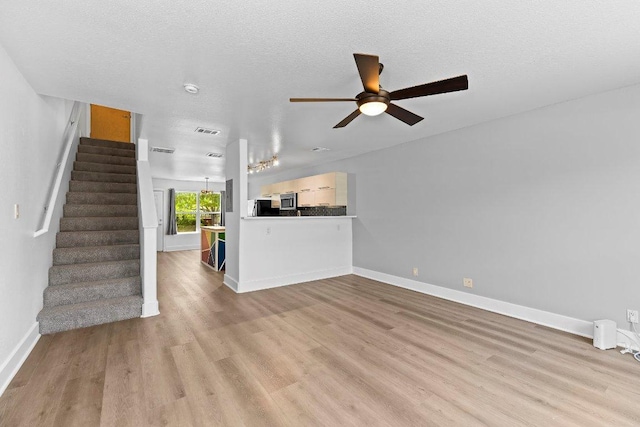 1101 Grove Blvd Unit 803, Austin, TX 78741 - unfurnished living room with a ceiling fan, wood finished floors, stairway, baseboards, and a textured ceiling