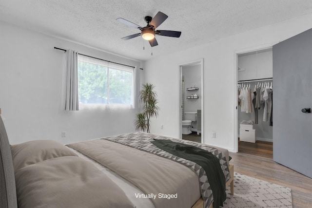 4406 Dove Springs Dr, Austin, TX 78744 - bedroom with wood finished floors, a walk in closet, a textured ceiling, ensuite bath, and a closet