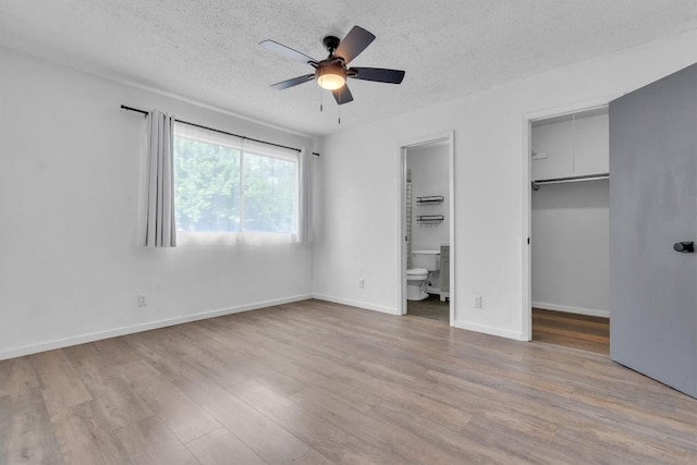 4406 Dove Springs Dr, Austin, TX 78744 - unfurnished bedroom featuring a walk in closet, wood finished floors, a textured ceiling, ensuite bath, and a closet