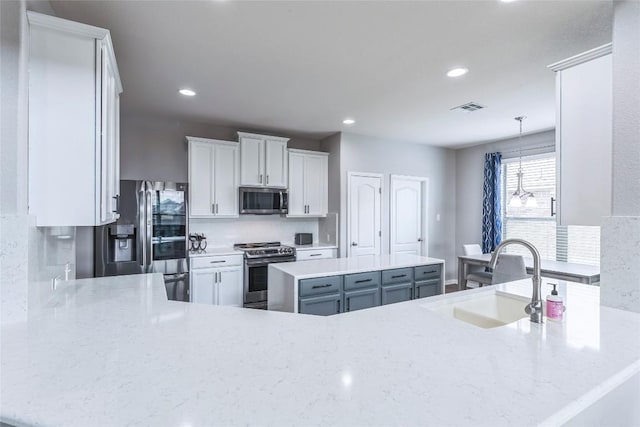 302 Emory Fields Dr, Hutto, TX 78634 - kitchen featuring stainless steel appliances, a sink, recessed lighting, white cabinets, and decorative light fixtures