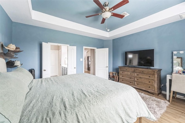 302 Emory Fields Dr, Hutto, TX 78634 - bedroom with a raised ceiling, wood finished floors, baseboards, ceiling fan, and ensuite bath