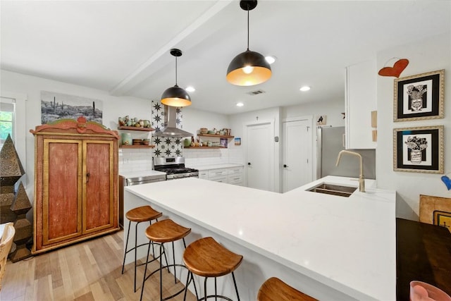 2406 Shiloh Dr, Austin, TX 78745 - kitchen with open shelves, appliances with stainless steel finishes, a peninsula, a sink, and light wood finished floors