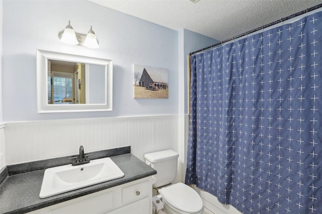 17008 Cactus Blossom Dr, Pflugerville, TX 78660 - bathroom featuring vanity, toilet, a textured ceiling, wainscoting, and shower / tub combo