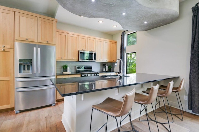 1904 E 9th St, Austin, TX 78702 - kitchen with appliances with stainless steel finishes, light brown cabinets, backsplash, a sink, and light wood-type flooring