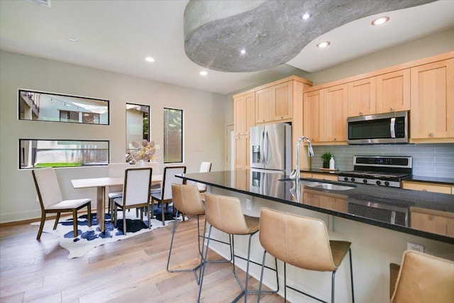 1904 E 9th St, Austin, TX 78702 - kitchen featuring appliances with stainless steel finishes, a sink, light brown cabinetry, light wood-style flooring, and recessed lighting