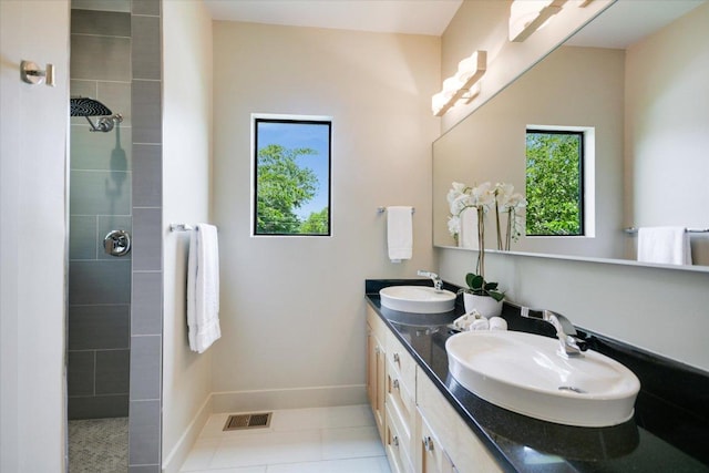 1904 E 9th St, Austin, TX 78702 - bathroom featuring double vanity, a tile shower, tile patterned floors, and baseboards
