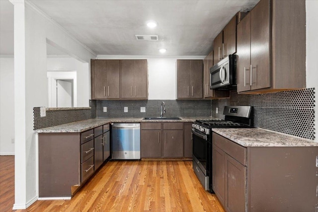 1307 Meadgreen Dr, Austin, TX 78758 - kitchen featuring stainless steel appliances, a sink, light wood-style floors, tasteful backsplash, and light stone countertops