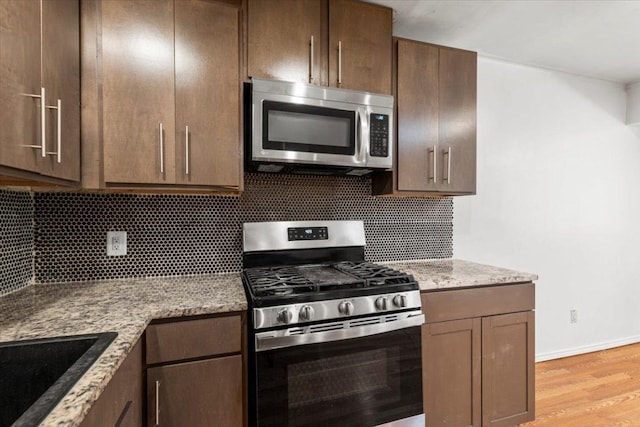 1307 Meadgreen Dr, Austin, TX 78758 - kitchen with stainless steel appliances, tasteful backsplash, light wood-style flooring, and light stone countertops