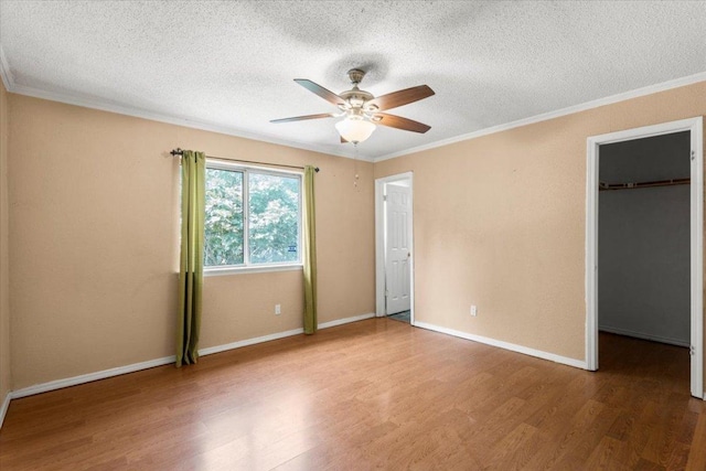 1307 Meadgreen Dr, Austin, TX 78758 - unfurnished bedroom with wood finished floors, a textured ceiling, a spacious closet, ornamental molding, and baseboards