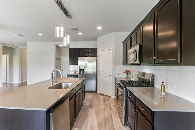4333 Buffalo Ford Rd, Georgetown, TX 78628 - kitchen featuring appliances with stainless steel finishes, light wood-type flooring, hanging light fixtures, decorative backsplash, and light countertops