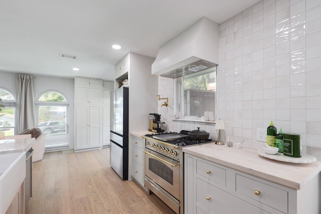 7905 Havenwood Dr, Austin, TX 78759 - kitchen featuring stainless steel appliances, custom range hood, decorative backsplash, light wood-style flooring, and recessed lighting