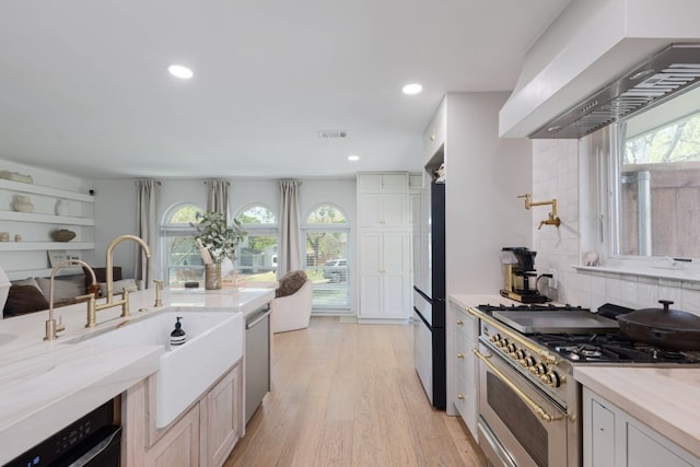 7905 Havenwood Dr, Austin, TX 78759 - kitchen featuring appliances with stainless steel finishes, wall chimney exhaust hood, healthy amount of natural light, light wood-style floors, and recessed lighting