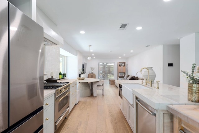 7905 Havenwood Dr, Austin, TX 78759 - kitchen featuring appliances with stainless steel finishes, light wood-type flooring, recessed lighting, open floor plan, and pendant lighting