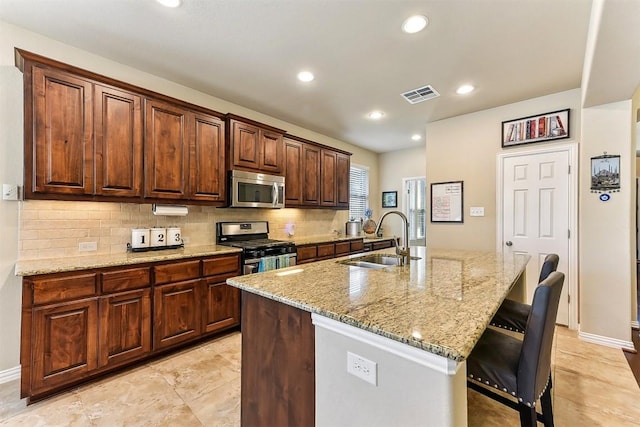 2415 Berkshire Way, Cedar Park, TX 78613 - kitchen featuring stainless steel appliances, decorative backsplash, an island with sink, light stone counters, and a breakfast bar