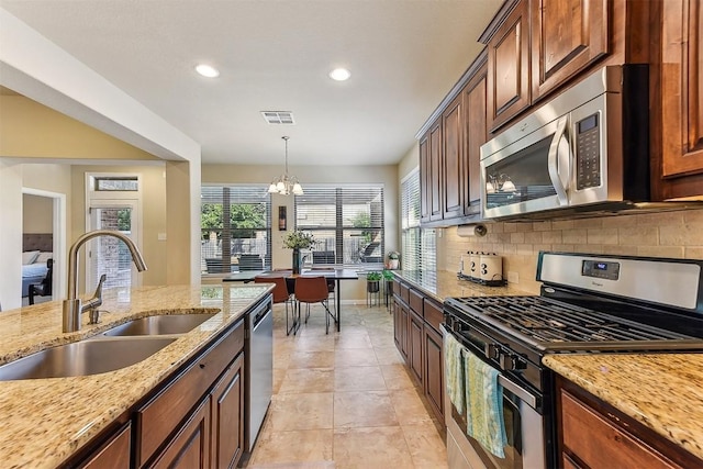 2415 Berkshire Way, Cedar Park, TX 78613 - kitchen with stainless steel appliances, backsplash, a chandelier, light stone countertops, and decorative light fixtures