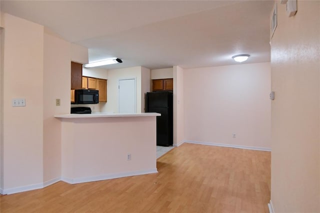 2450 Wickersham Ln Unit 718, Austin, TX 78741 - kitchen featuring black appliances, light wood-type flooring, and baseboards