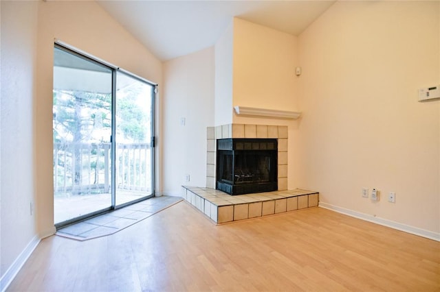 2450 Wickersham Ln Unit 718, Austin, TX 78741 - unfurnished living room featuring wood finished floors, a fireplace, baseboards, and vaulted ceiling