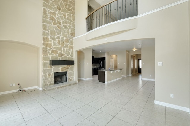 2937 Castellan Ln, Round Rock, TX 78665 - unfurnished living room with light tile patterned flooring, a high ceiling, a stone fireplace, and arched walkways