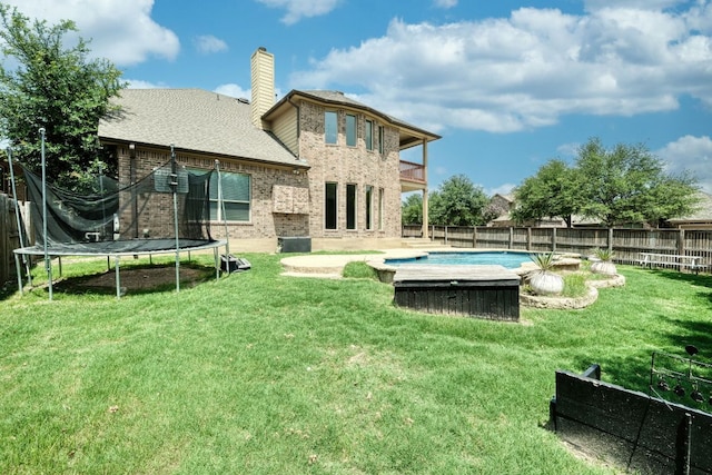 2937 Castellan Ln, Round Rock, TX 78665 - rear view of house featuring a trampoline, a fenced backyard, brick siding, a chimney, and a balcony