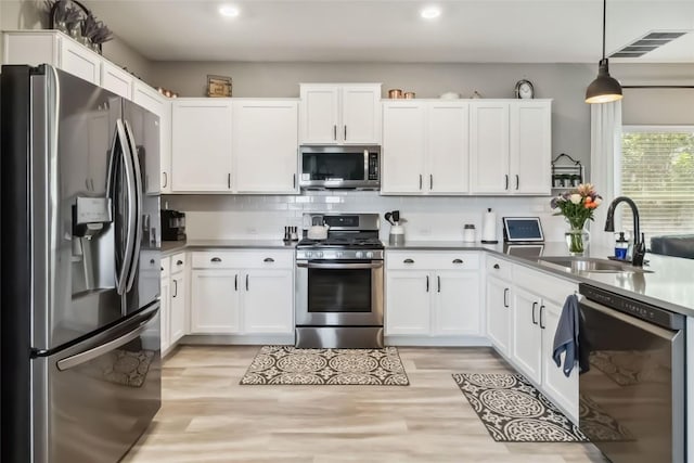 10901 Rome Ave, Austin, TX 78747 - kitchen with stainless steel appliances, recessed lighting, white cabinetry, tasteful backsplash, and light wood-style floors
