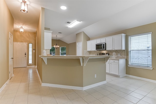 168 Hickory Ln, Georgetown, TX 78633 - kitchen with stainless steel microwave, vaulted ceiling, a breakfast bar, white cabinetry, and light tile patterned floors