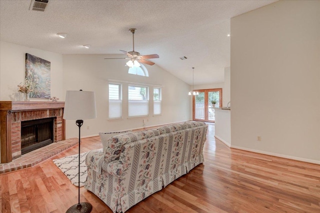 7925 Wheel Rim Cir, Austin, TX 78749 - living room featuring wood finished floors, a fireplace, lofted ceiling, ceiling fan, and a textured ceiling