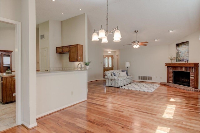 7925 Wheel Rim Cir, Austin, TX 78749 - living area with light wood-style floors, ceiling fan, a chandelier, a fireplace, and baseboards