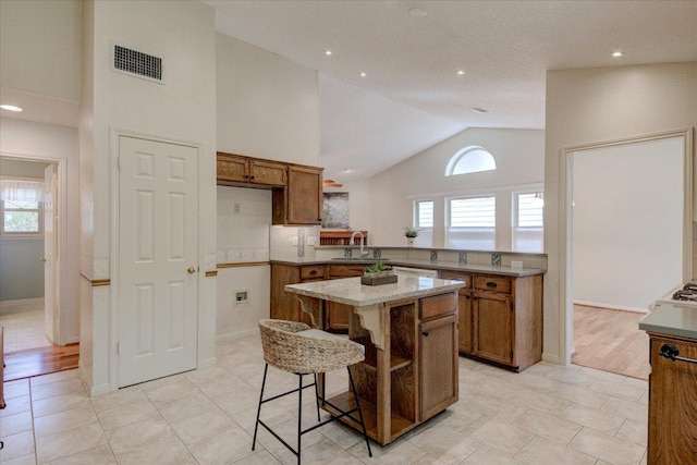 7925 Wheel Rim Cir, Austin, TX 78749 - kitchen with brown cabinets, healthy amount of natural light, high vaulted ceiling, a kitchen breakfast bar, and a center island