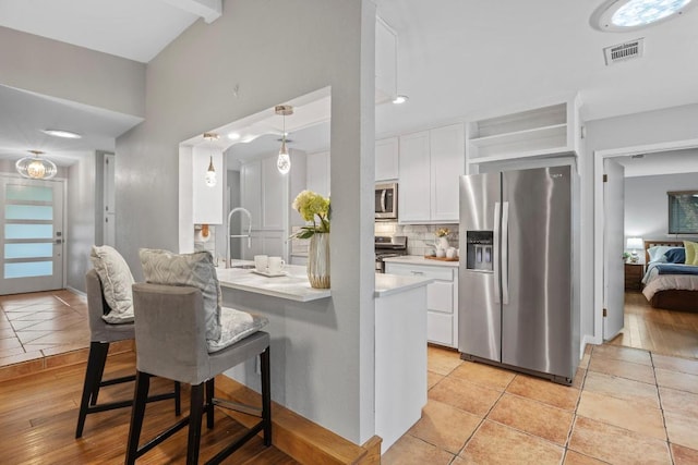 11505 Circle Bend Dr, Austin, TX 78758 - kitchen featuring stainless steel appliances, white cabinets, light countertops, a breakfast bar area, and decorative backsplash