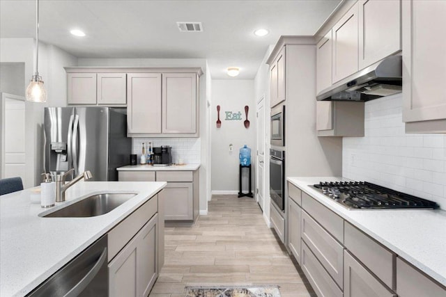 129 Lacey Oak Loop, San Marcos, TX 78666 - kitchen featuring stainless steel appliances, a sink, under cabinet range hood, tasteful backsplash, and decorative light fixtures