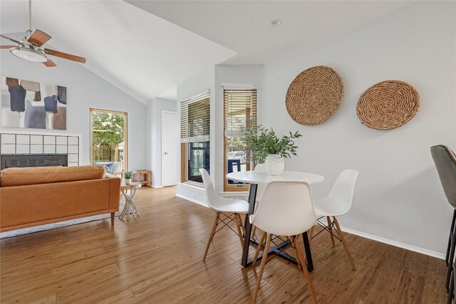 12319 Emery Oaks Rd, Austin, TX 78758 - dining area featuring a fireplace, ceiling fan, light wood-style floors, baseboards, and vaulted ceiling