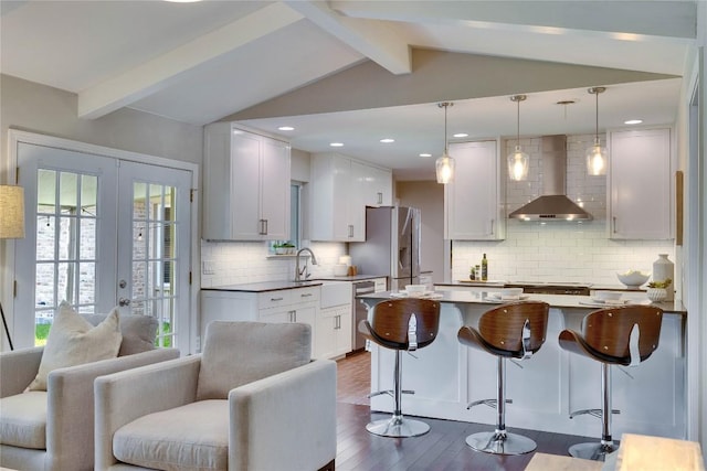 2905 Greenlawn Pkwy, Austin, TX 78757 - kitchen featuring wall chimney exhaust hood, dark wood-style floors, appliances with stainless steel finishes, open floor plan, and a kitchen bar