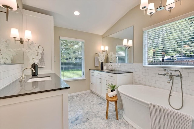 2905 Greenlawn Pkwy, Austin, TX 78757 - bathroom featuring lofted ceiling, two vanities, a soaking tub, a chandelier, and tile patterned flooring